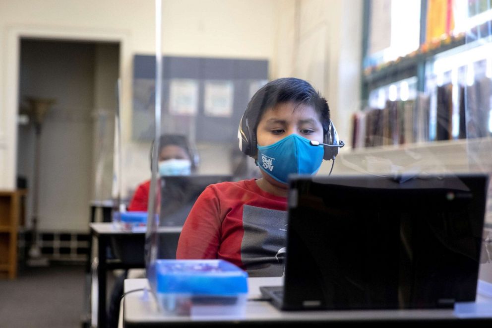PHOTO: A child wears a mask while using a computer from a socially-distanced desk during an in-person hybrid learning day at the Mount Vernon Community School in Alexandria, Va., March 2, 2021.