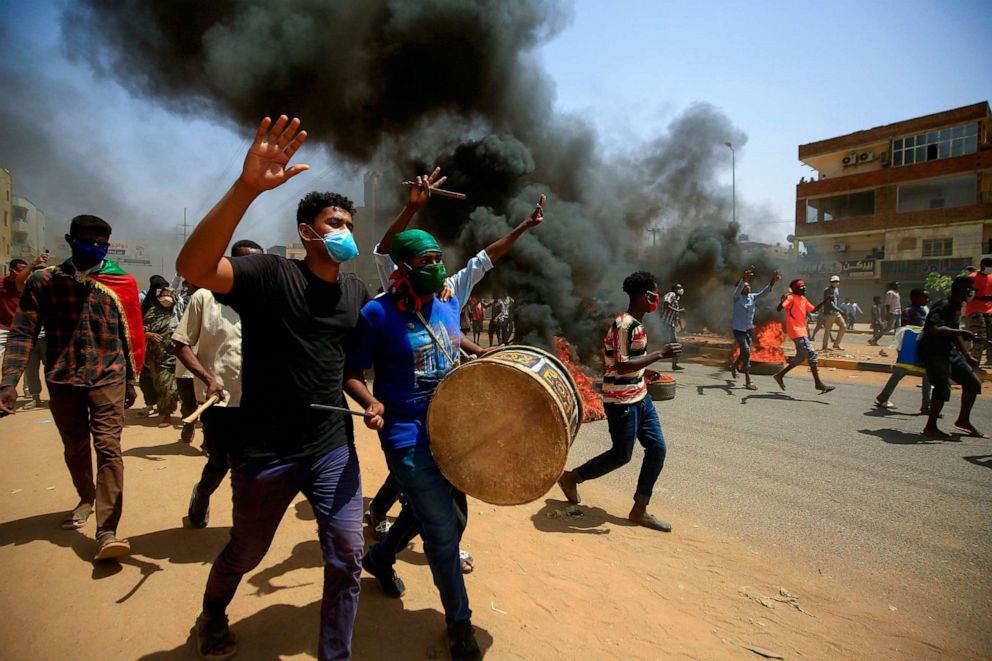 PHOTO: Sudanese demonstrators carrying a drum gesture as smoke billows from burning tires during a protest east of the capital Khartoum, Sudan, June 30, 2020.