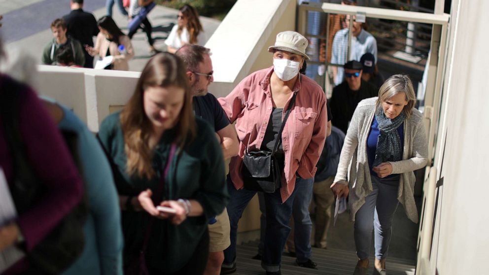 PHOTO: A woman wears a face mask as she lines up to vote at a polling station on Super Tuesday in Santa Monica, Calif., March 3, 2020.