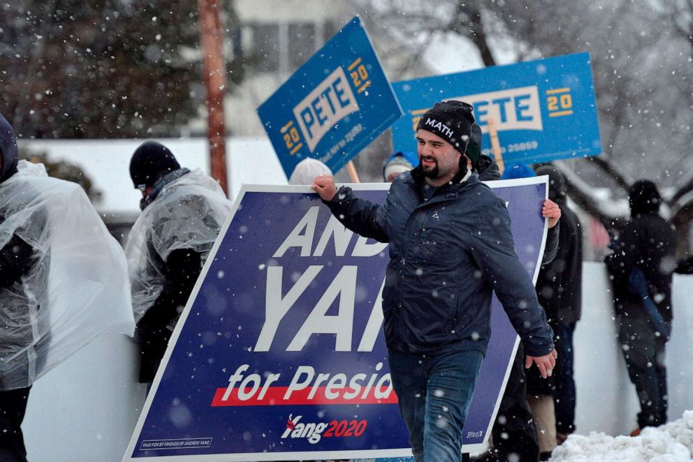 PHOTO: Supporters of Andrew Yang carry a sign as snow falls and people rally for their candidates outside of the Democratic Debate at St. Anselm College in Manchester, N.H., Feb. 7, 2020.
