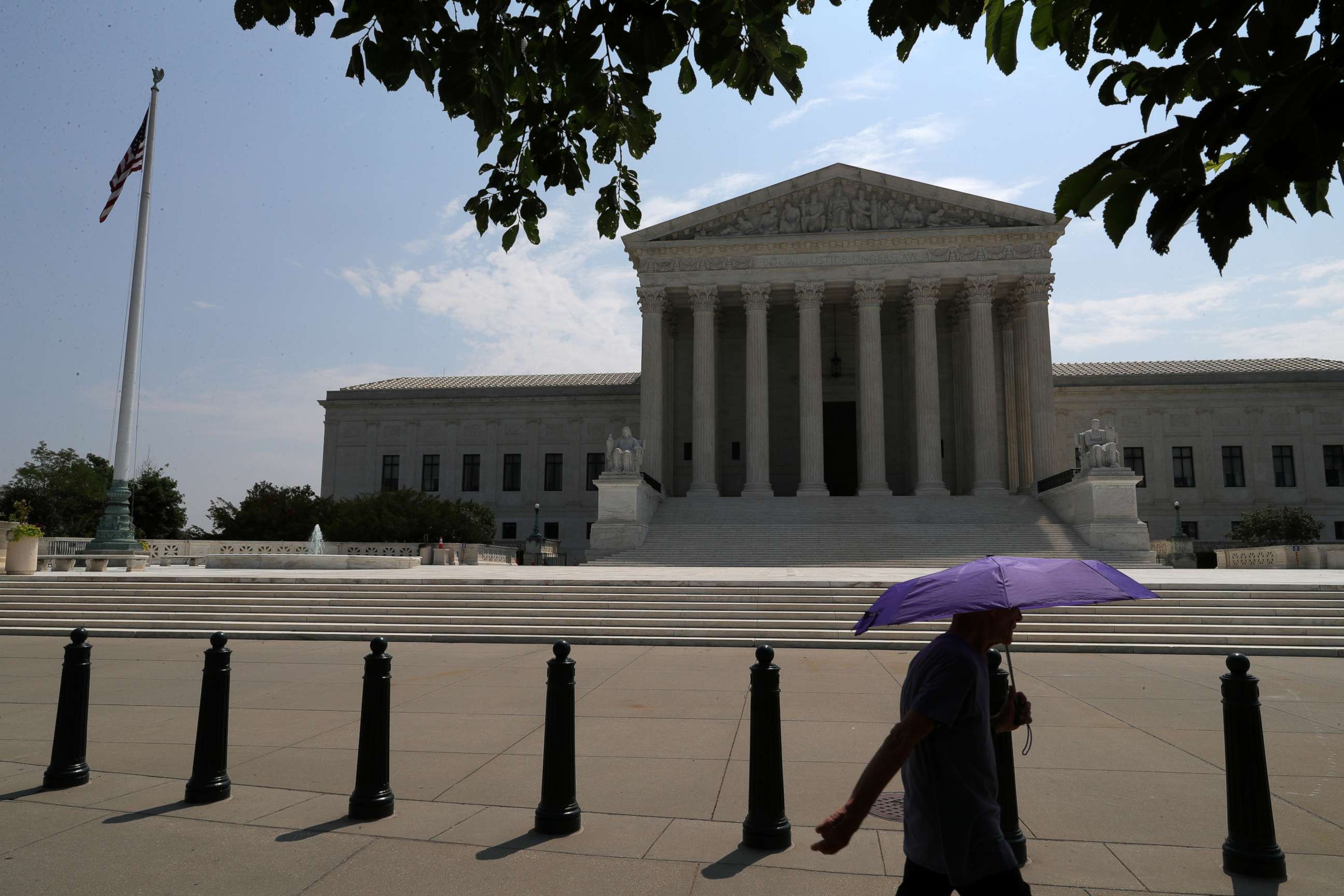 PHOTO: A pedestrian holding an umbrella walks along First Street, as a series of rulings are issued at the United States Supreme Court in Washington, July 6, 2020.
