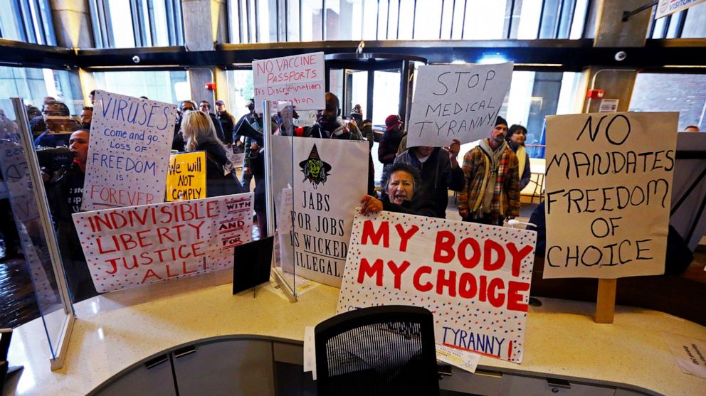 PHOTO: Protesters hold signs reading my body my choice, stop medical tyranny, and more, at City Hall in Boston, Dec. 20, 2021.