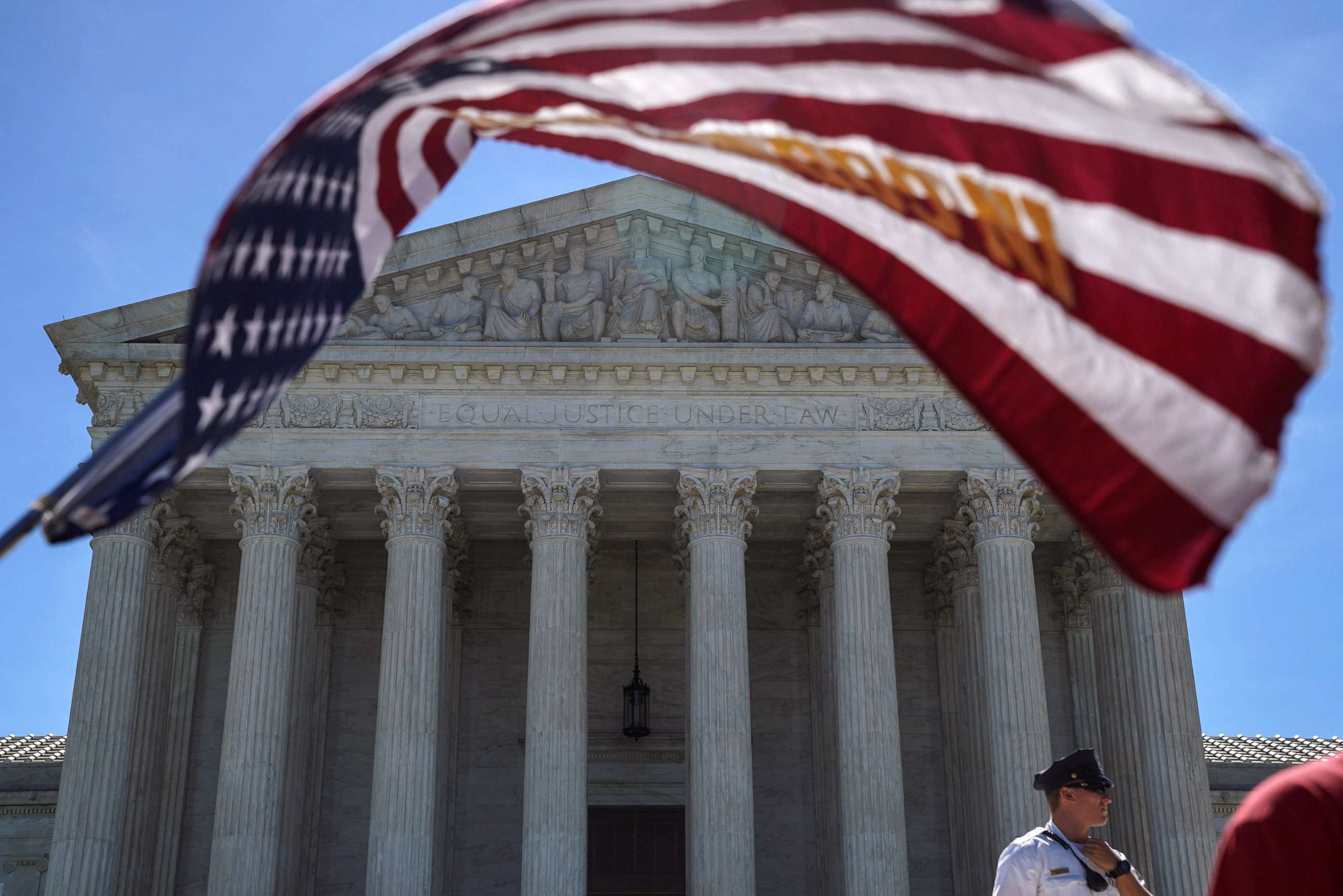 PHOTO: A man holds a flag outside the U.S. Supreme Court, as the Trump v. Hawaii case regarding travel restrictions in the U.S. remains pending, in Washington, D.C., June 25, 2018.