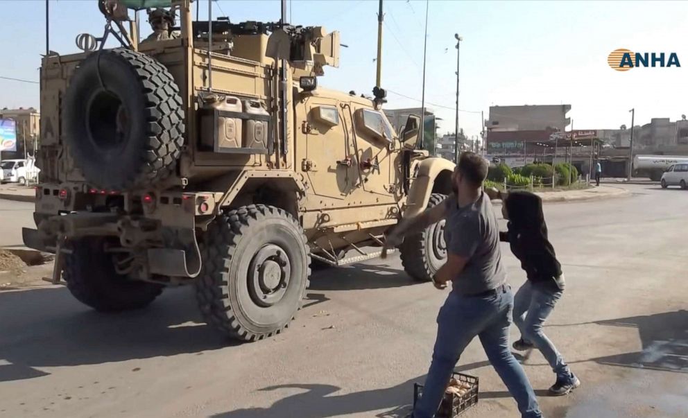 PHOTO: In this frame grab provided by Hawar News, ANHA, the Kurdish news agency, residents who are angry over the U.S. withdrawal from Syria hurl potatoes at American military vehicles in the town of Qamishli, northern Syria, Monday, Oct. 21, 2019.