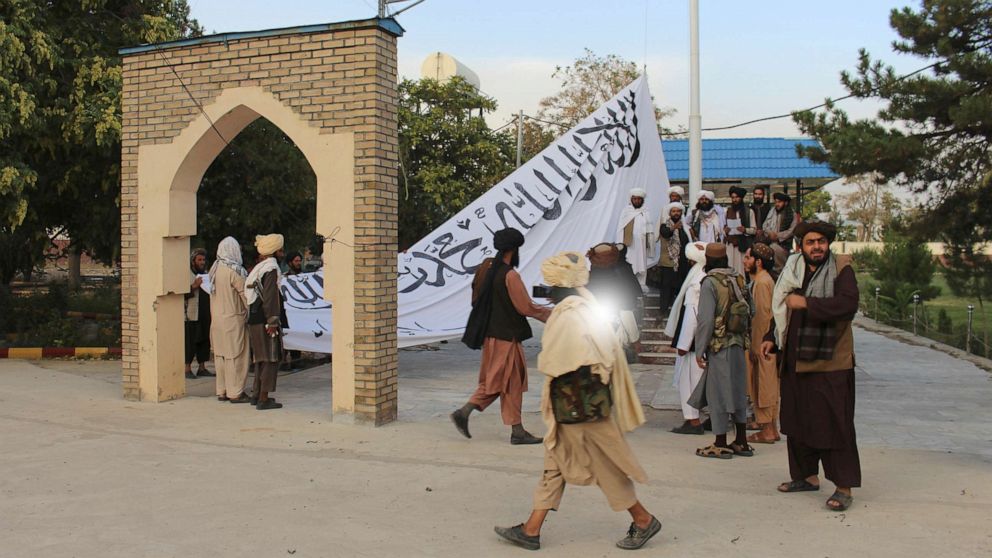 PHOTO: Taliban fighters raise their flag at the Ghazni provincial governor's house, in Ghazni, Afghanistan, Aug. 15, 2021.