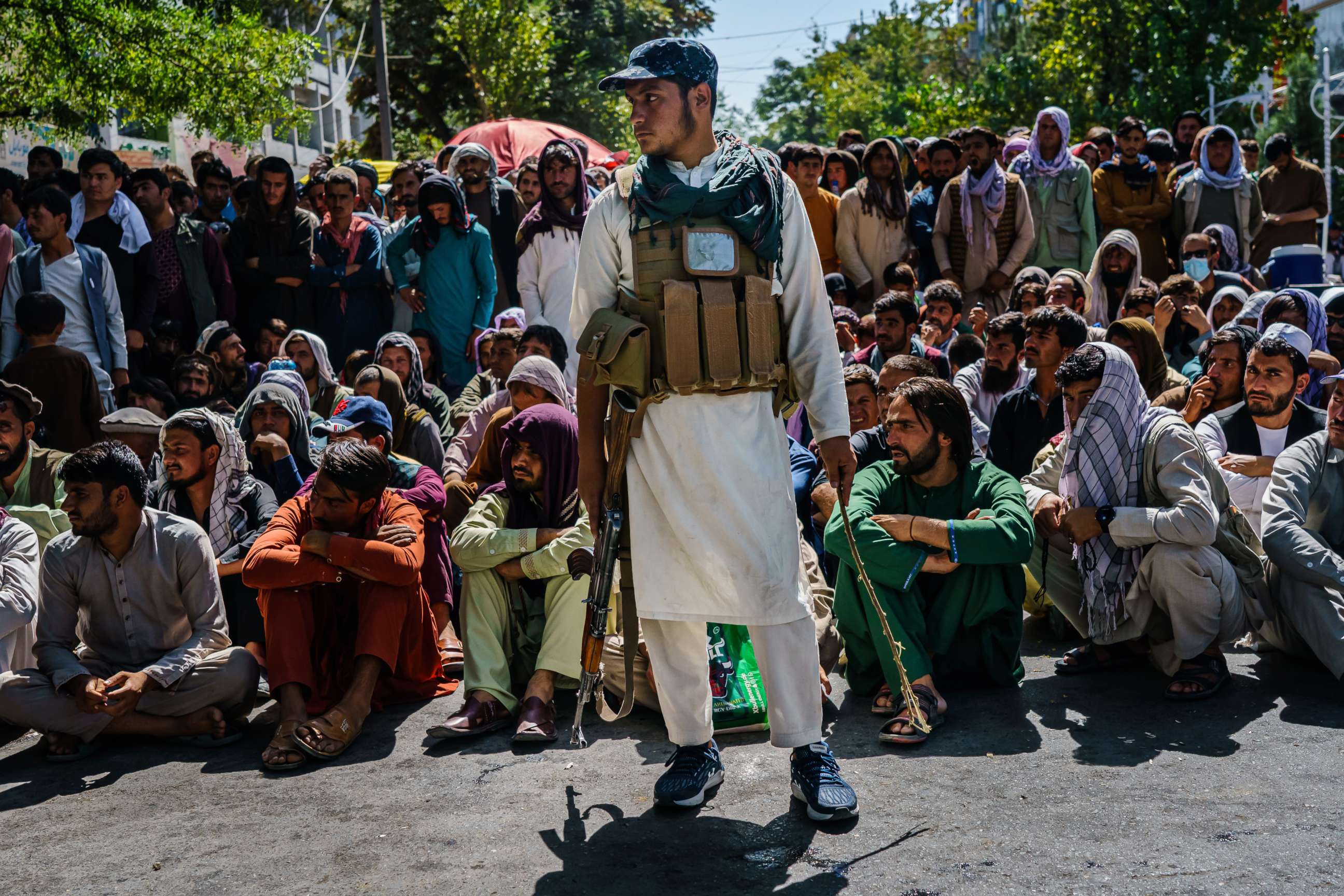 PHOTO: Guarded by Taliban militants, hundreds of Afghans are made to sit in the sweltering heat to withdraw money from the banks that are slowly reopening after Taliban took control of the country, in Kabul, Afghanistan, Sept. 5, 2021.