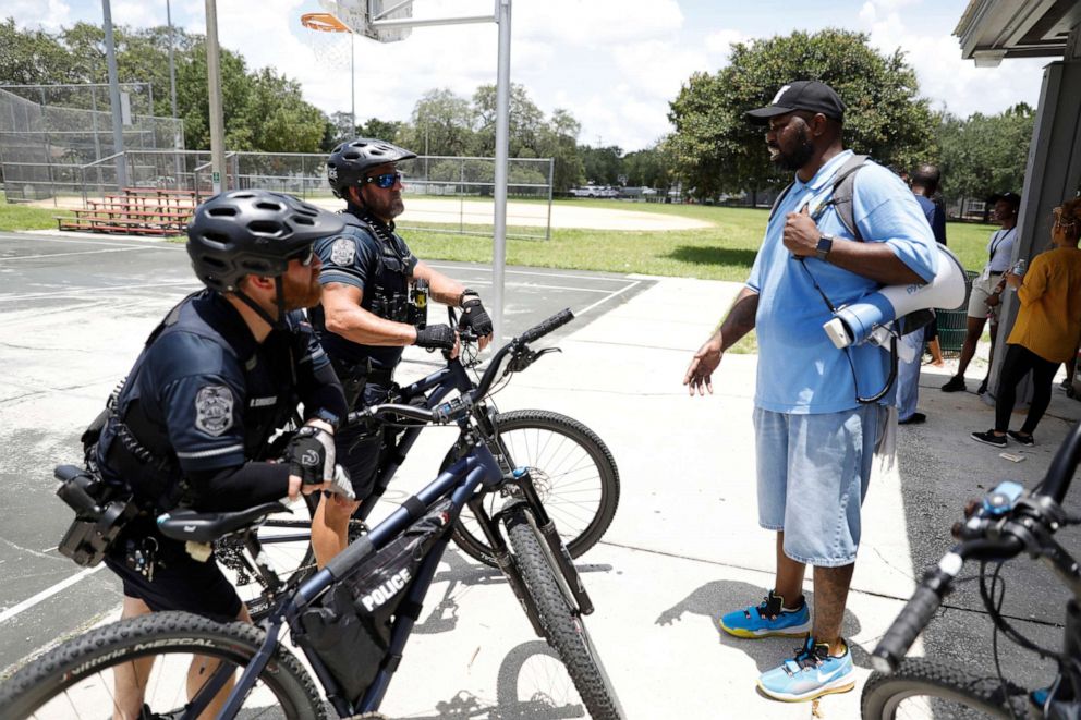 PHOTO: Johnnie Johnson from Rise Up for Peace, a non-profit organization talks with Tampa Police officers after going on a community peace walk in the Grant Park neighborhood, on June 26, 2021, in Tampa.