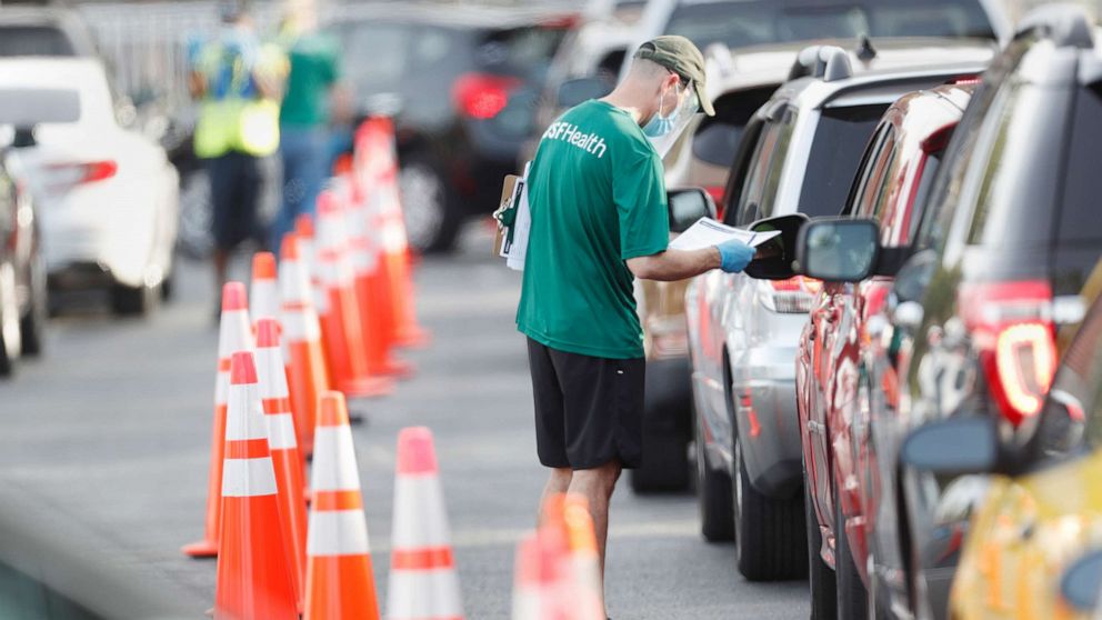 PHOTO: A University of South Florida (USF) Health administrator talks to a driver before they receive a coronavirus test at the Lee Davis Community Resource Center on June 25, 2020 in Tampa, Fla.