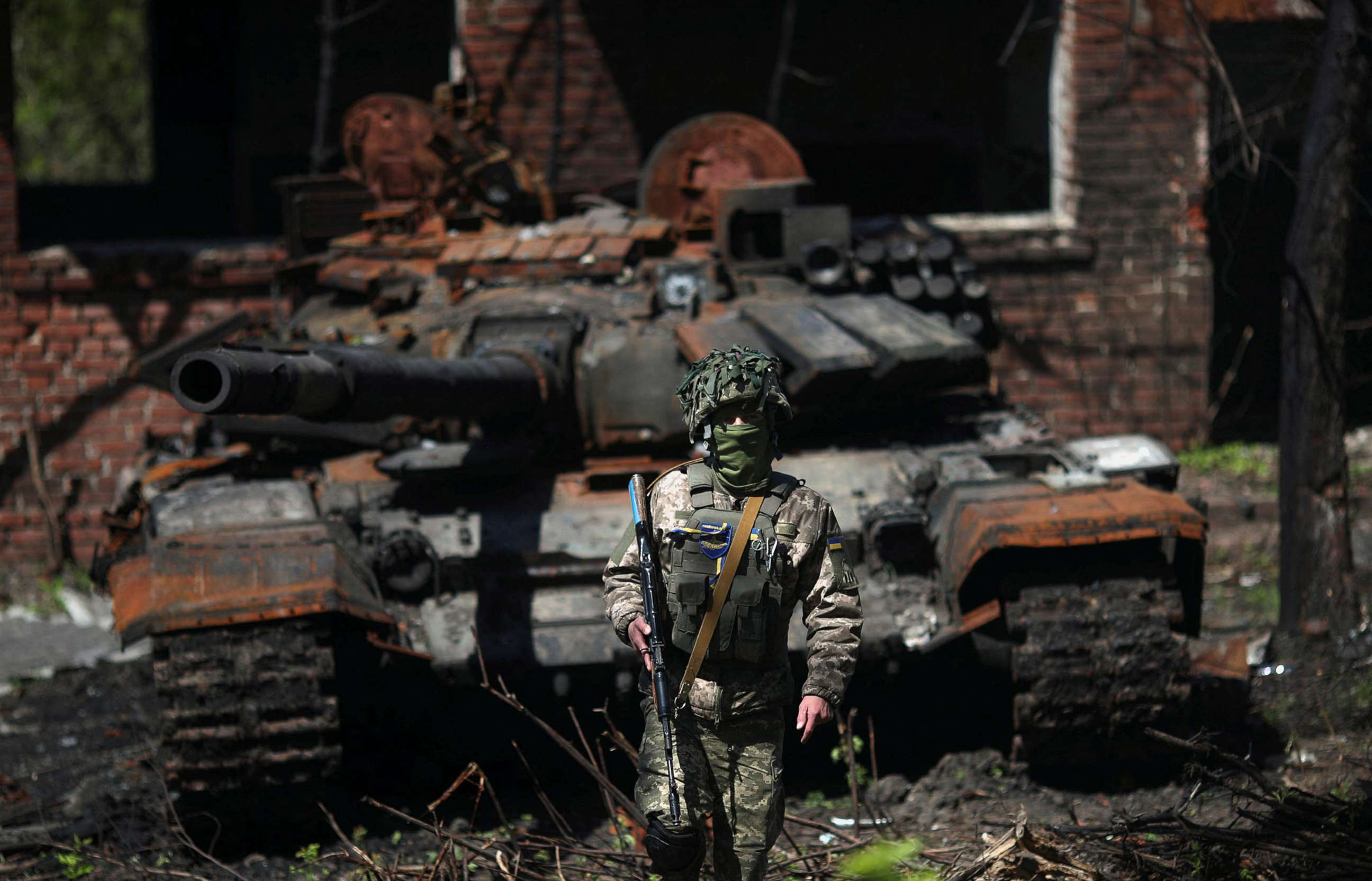 PHOTO: A Ukrainian soldier poses next to a destroyed Russian tank in Malaya Rohan village, amid Russia's attack on Ukraine, near Kharkiv, Ukraine, May 5, 2022. 