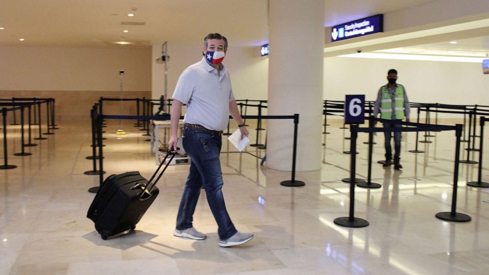 PHOTO: Sen. Ted Cruz carries his luggage at the Cancun International Airport before boarding his plane back to the U.S., Feb. 18, 2021, in Cancun, Mexico.