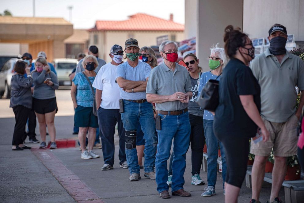 PHOTO: Voters wait in line outside of an Ace Hardware store in Odessa, Texas, for the first day of early voting in Texas on Tuesday, Oct. 13, 2020. 