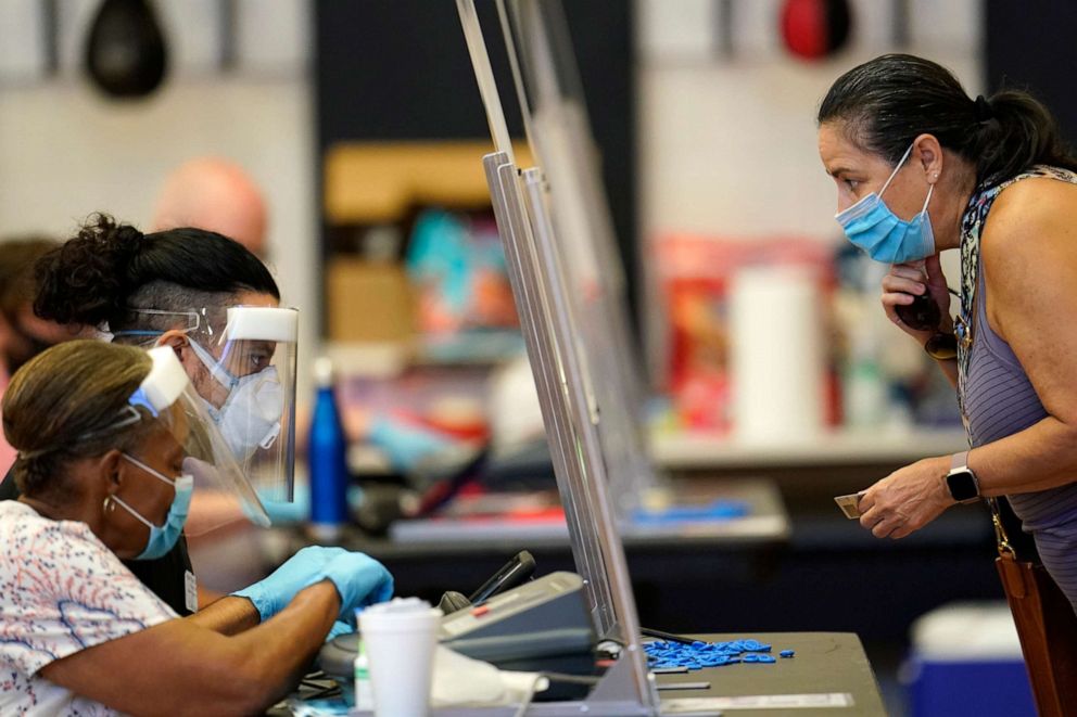 PHOTO: A voter, right, shows her identification to a Harris County election clerk before voting, in Houston, July 14, 2020.