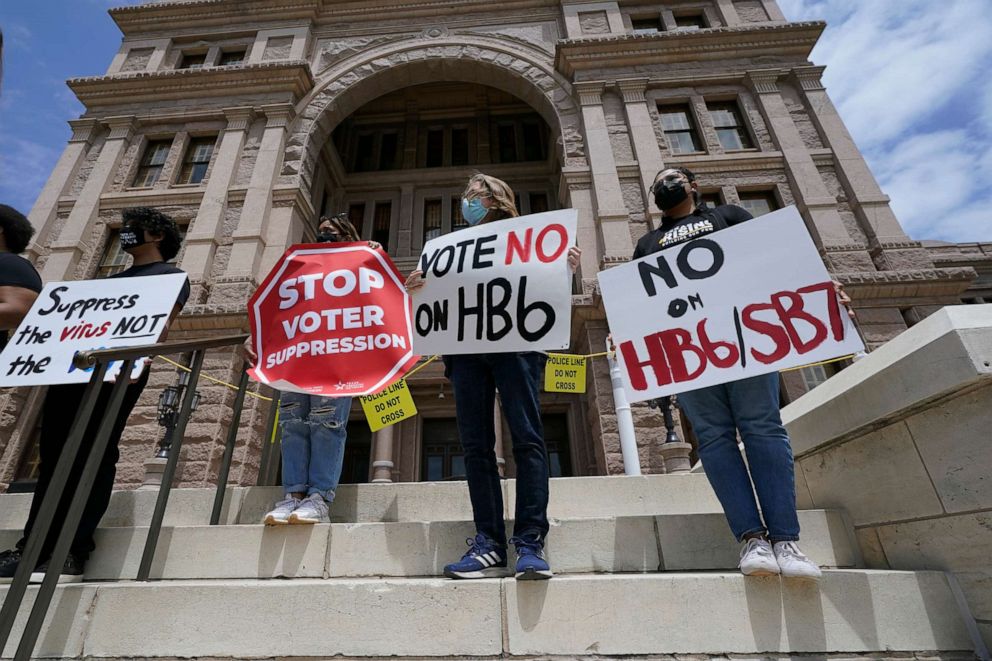People opposed to Texas voter bills HB6 and SB7 hold signs during a news conference hosted by Texas Rising Action on the steps of the State Capitol on April 21, 2021, in Austin, Texas.