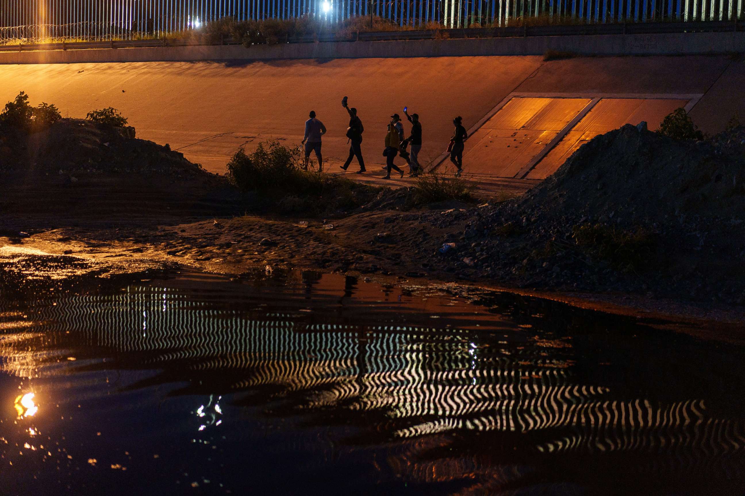 PHOTO: Migrants walk along the border wall after crossing into El Paso, Texas, from Ciudad Juarez, Chihuahua state, Mexico, Sept. 22, 2022.