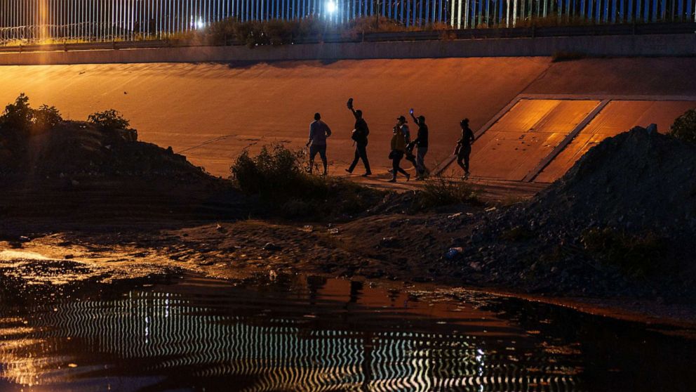 PHOTO: Migrants walk along the border wall after crossing into El Paso, Texas, from Ciudad Juarez, Chihuahua state, Mexico, Sept. 22, 2022.