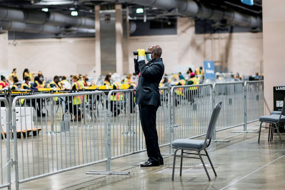 PHOTO: An official poll watcher uses binoculars as workers count ballots for the 2020 Presidential in Philadelphia, Nov. 3, 2020. 