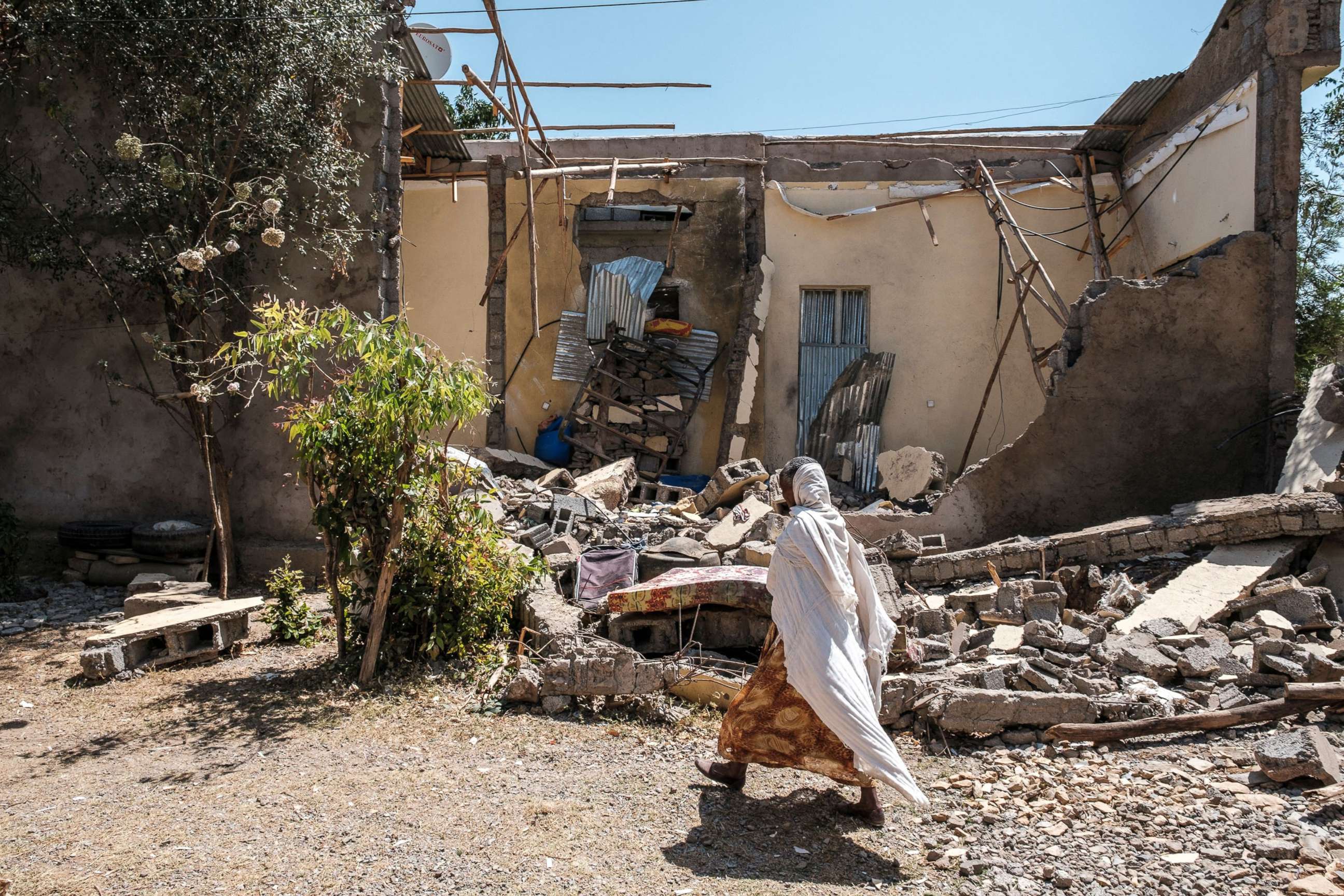 PHOTO: A woman walks in front of a damaged house which was shelled as federal-aligned forces entered the city, in Wukro, north of Mekele, March 1, 2021.