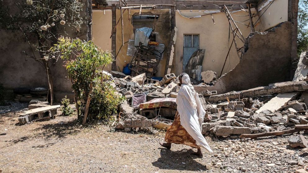 PHOTO: A woman walks in front of a damaged house which was shelled as federal-aligned forces entered the city, in Wukro, north of Mekele, March 1, 2021.