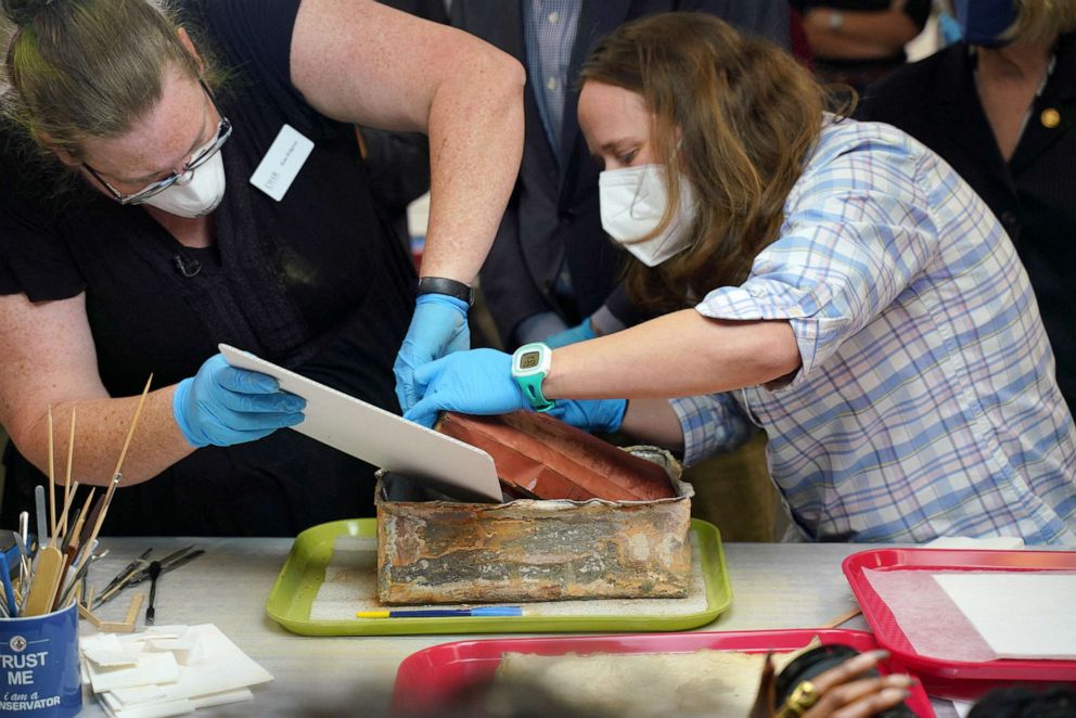 PHOTO: Kate Ridgeway and Sue Donovan, conservators with the Virginia Department of Historic Resources, remove one of three books found in a time capsule recovered from Confederate General Robert E. Lee's monument in Richmond, Va, Dec. 22, 2021.  