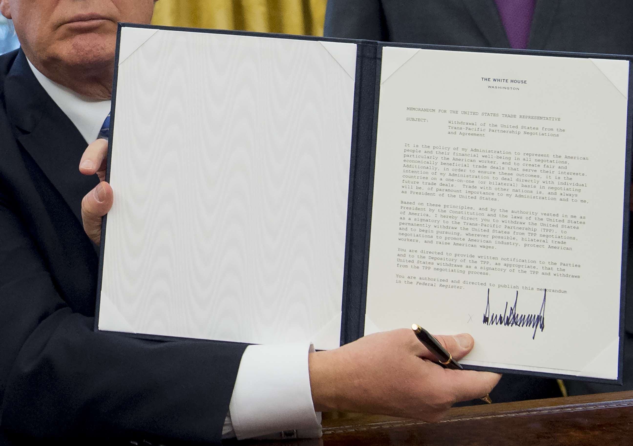 PHOTO: President Donald Trump holds up an executive order withdrawing the US from the Trans-Pacific Partnership after signing it in the Oval Office of the White House in Washington, DC, Jan. 23, 2017.