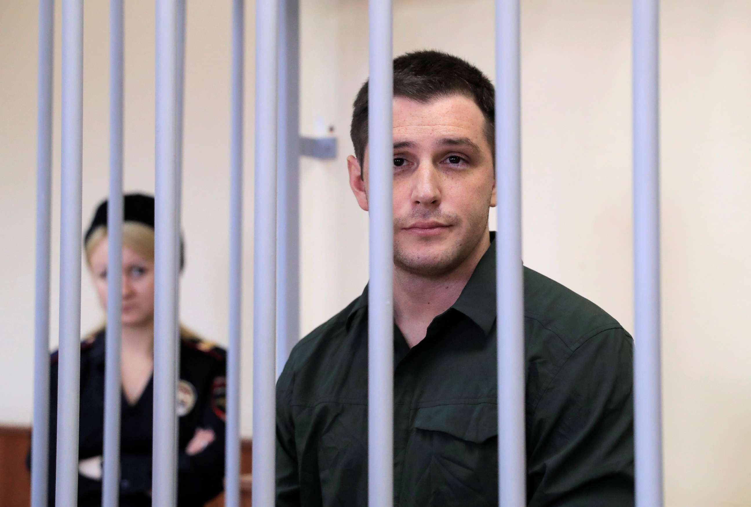 PHOTO: U.S. ex-Marine Trevor Reed, who was detained in 2019 and accused of assaulting police officers, stands inside a defendants' cage during a court hearing in Moscow, March 11, 2020.