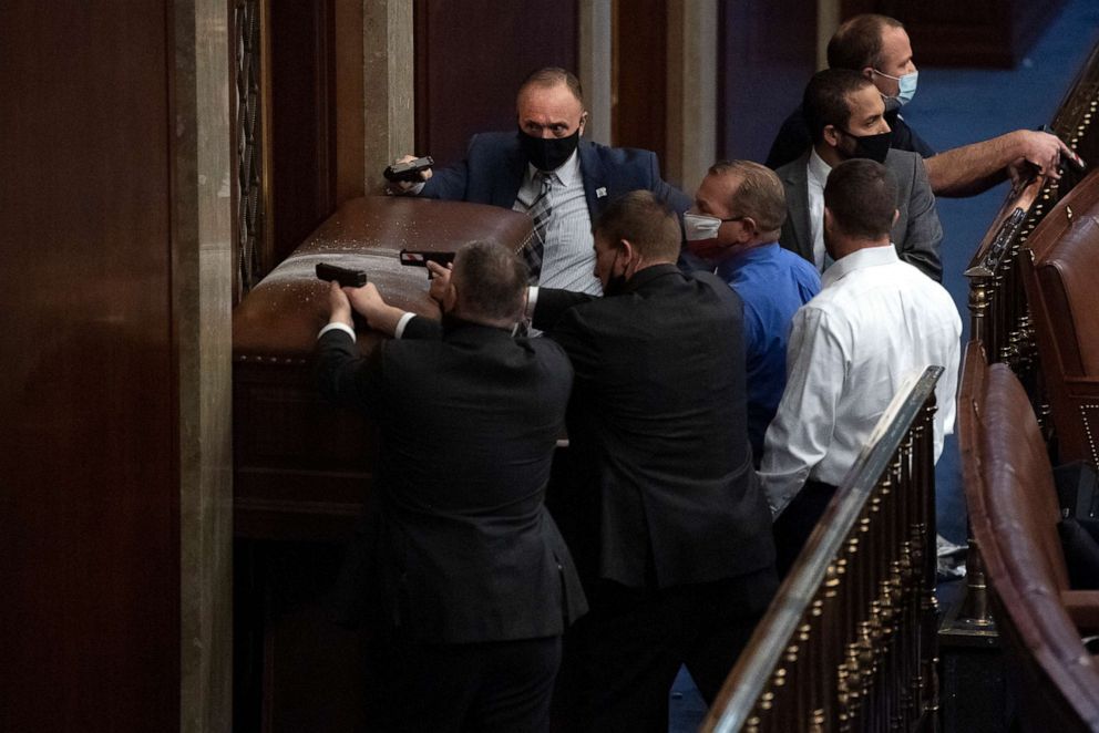 Security personnel barricade the door of the House chamber as rioters disrupt the joint session of Congress to certify the Electoral College vote on Jan. 6, 2021. Reps. Troy Nehls, R-Texas, blue shirt, and Markwayne Mullin, R-Okla., right, are also seen.
