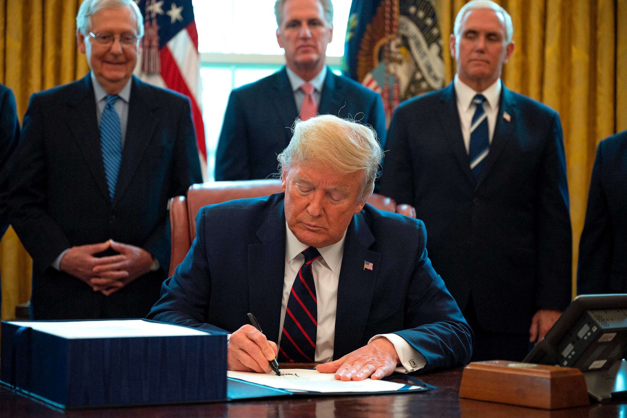 PHOTO: President Donald Trump signs the CARES act, a $2 trillion rescue package to provide economic relief amid the coronavirus outbreak, at the Oval Office of the White House on March 27, 2020.