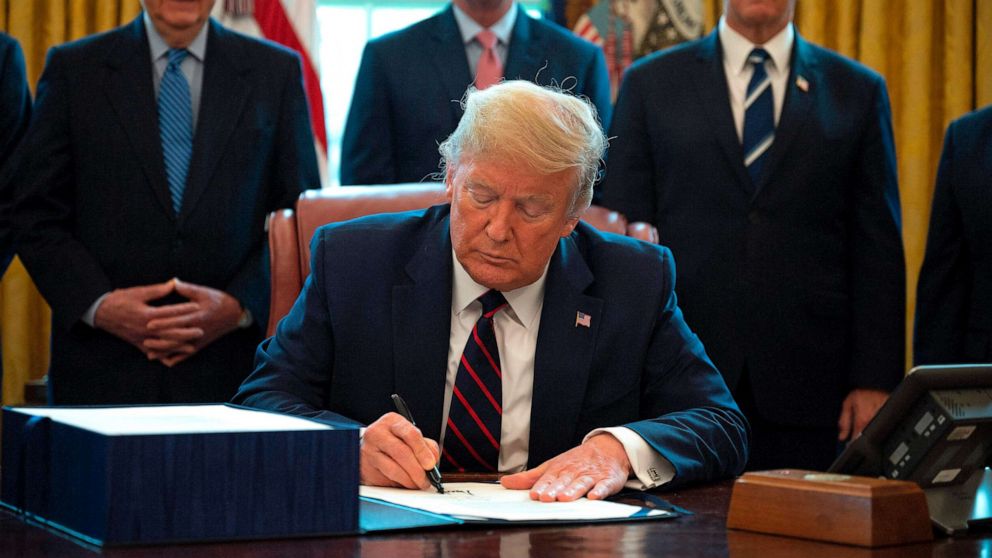 PHOTO: President Donald Trump signs the CARES act, a $2 trillion rescue package to provide economic relief amid the coronavirus outbreak, at the Oval Office of the White House on March 27, 2020.