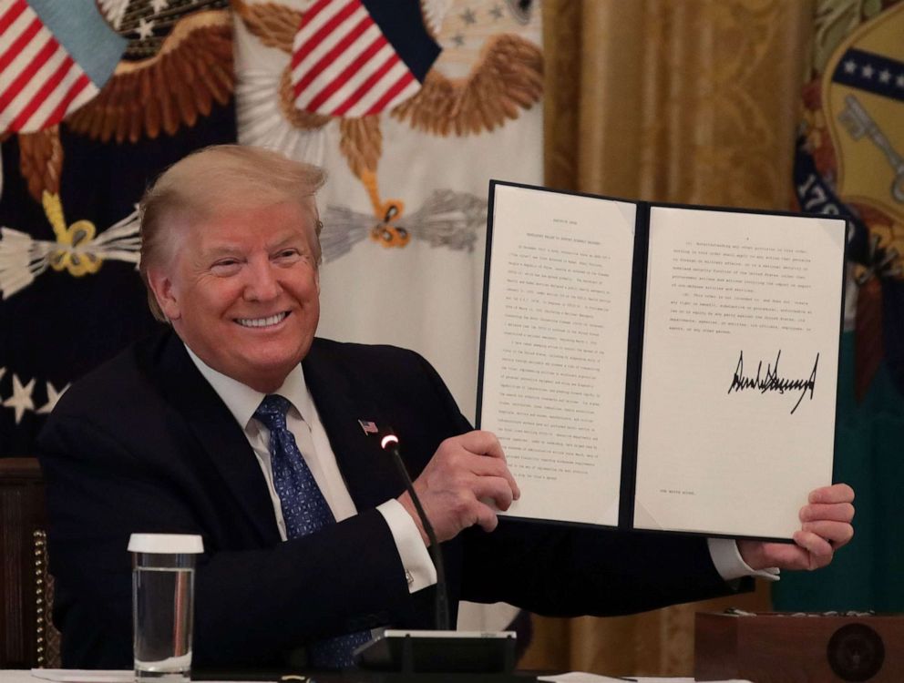 PHOTO: President Donald Trump holds up a copy of an executive order he signed on DOT deregulation, during a meeting with his cabinet in the East Room of the White House, May 19, 2020.