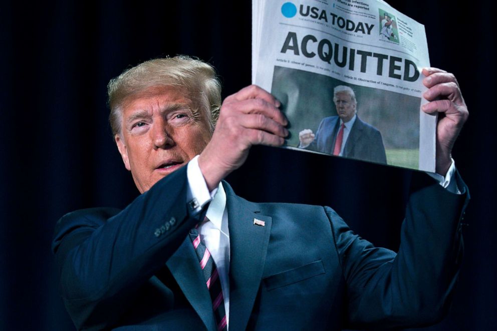 PHOTO: President Donald Trump holds up a newspaper with the headline that reads "ACQUITTED" during the 68th annual National Prayer Breakfast, Feb. 6, 2020, in Washington, D.C. 