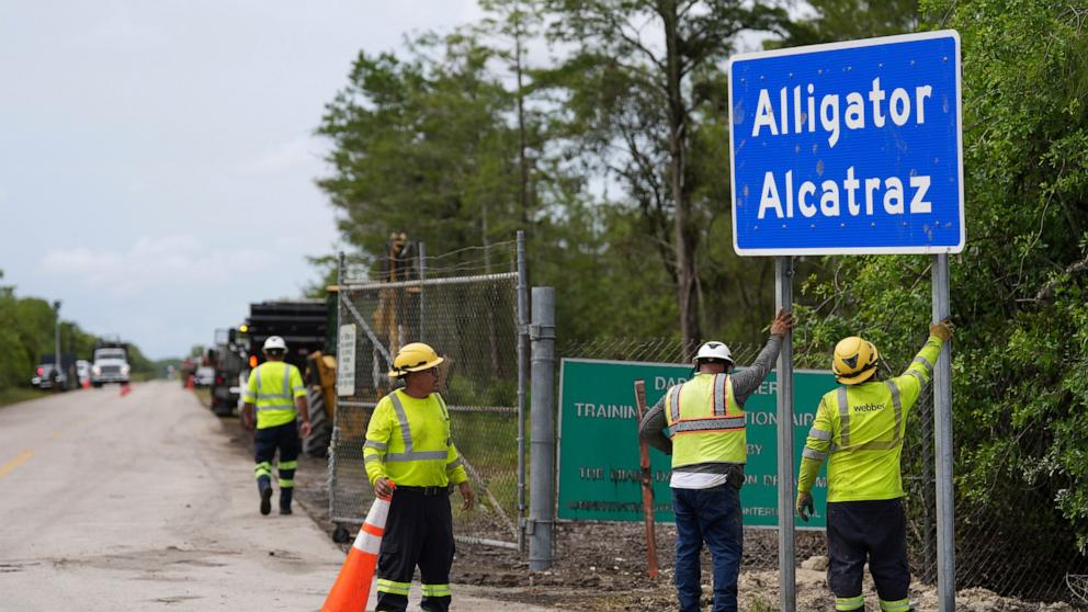 PHOTO: Workers install a sign reading "Alligator Alcatraz" at the entrance to a new migrant detention facility at Dade-Collier Training and Transition facility, July 3, 2025, in Ochopee, Fla.