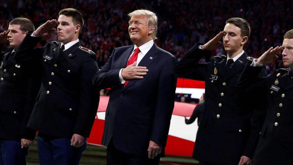 President Donald Trump stands with ROTC students to participate in the national anthem before the NCAA College Football Playoff Championship game between Alabama and Georgia in Atlanta, Jan. 8, 2018.Ernst