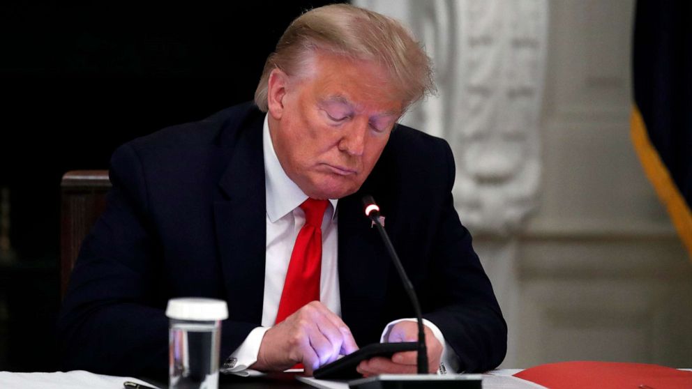 PHOTO: In this June 18, 2020, file photo, President Donald Trump looks at his phone in the State Dining Room of the White House in Washington, D.C.