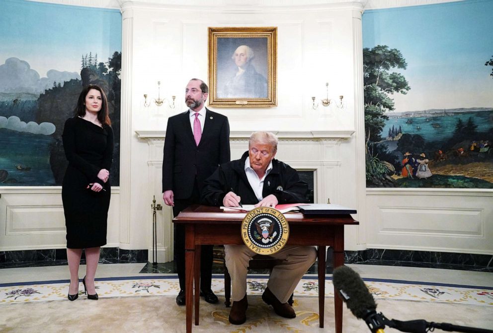 PHOTO: President Donald Trump signs an emergency funding bill to combat COVID-19, coronavirus, as Health Secretary Alex Azar looks on in the Diplomatic Room of the White House in Washington, March 6, 2020.