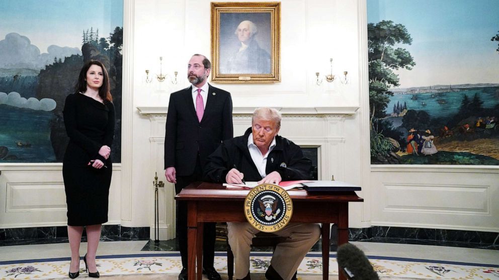 PHOTO: President Donald Trump signs an emergency funding bill to combat COVID-19, coronavirus, as Health Secretary Alex Azar looks on in the Diplomatic Room of the White House, March 6, 2020.