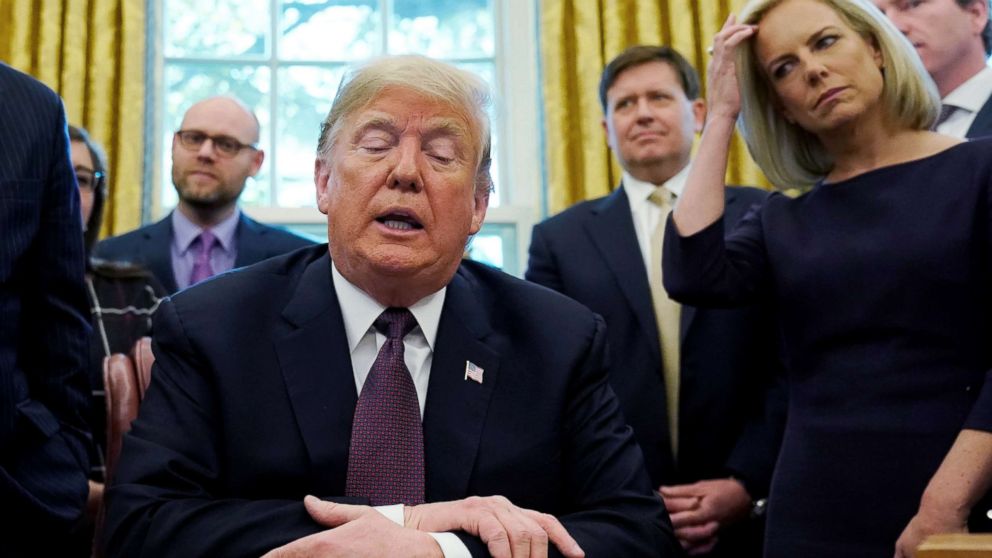 PHOTO: President Donald Trump talks to reporters as Department of Homeland Security Secretary Kirstjen Nielsen, right, looks on at a signing ceremony in the Oval Office of the White House, Nov. 16, 2018.