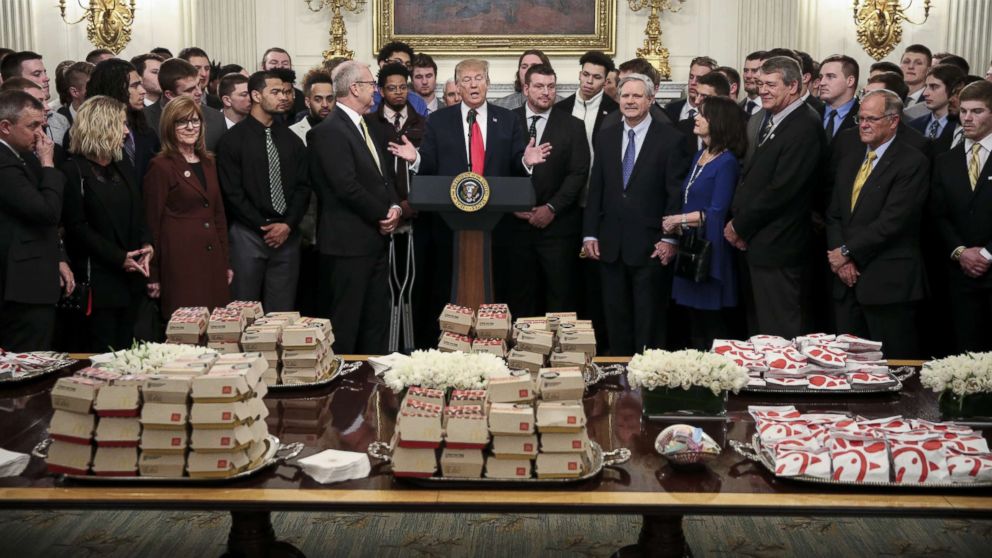 PHOTO: President Donald Trump speaks behind a table full of McDonald's hamburgers as he welcomes the 2018 Football Division I FCS champs North Dakota State Bison in the Diplomatic Room of the White House, March 4, 2019.