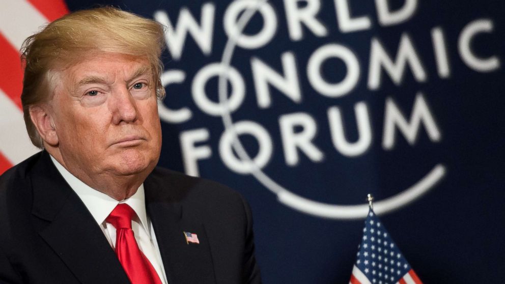 President Donald Trump looks on as he sits next to the logo of the World Economic Forum annual meeting, Jan. 26, 2018, in Davos, Switzerland.