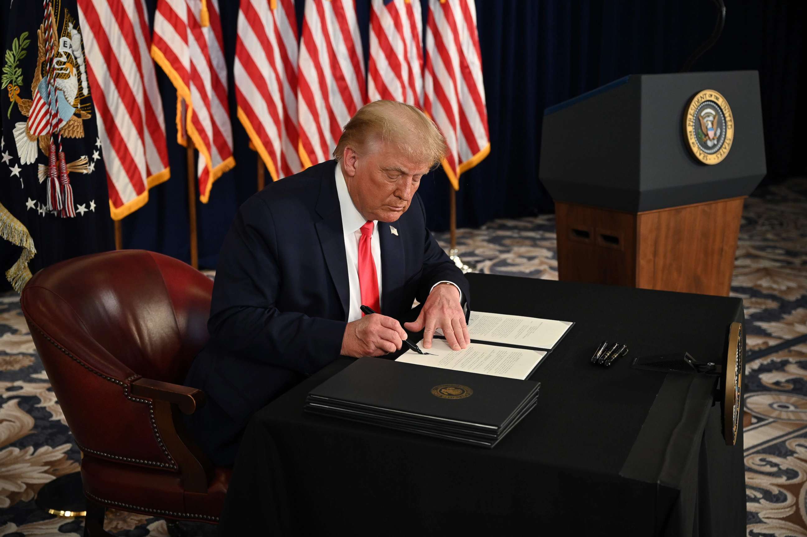 PHOTO: President Donald Trump signs an executive orders extending coronavirus economic relief, during a news conference in Bedminster, N.J., on Aug.8, 2020.
