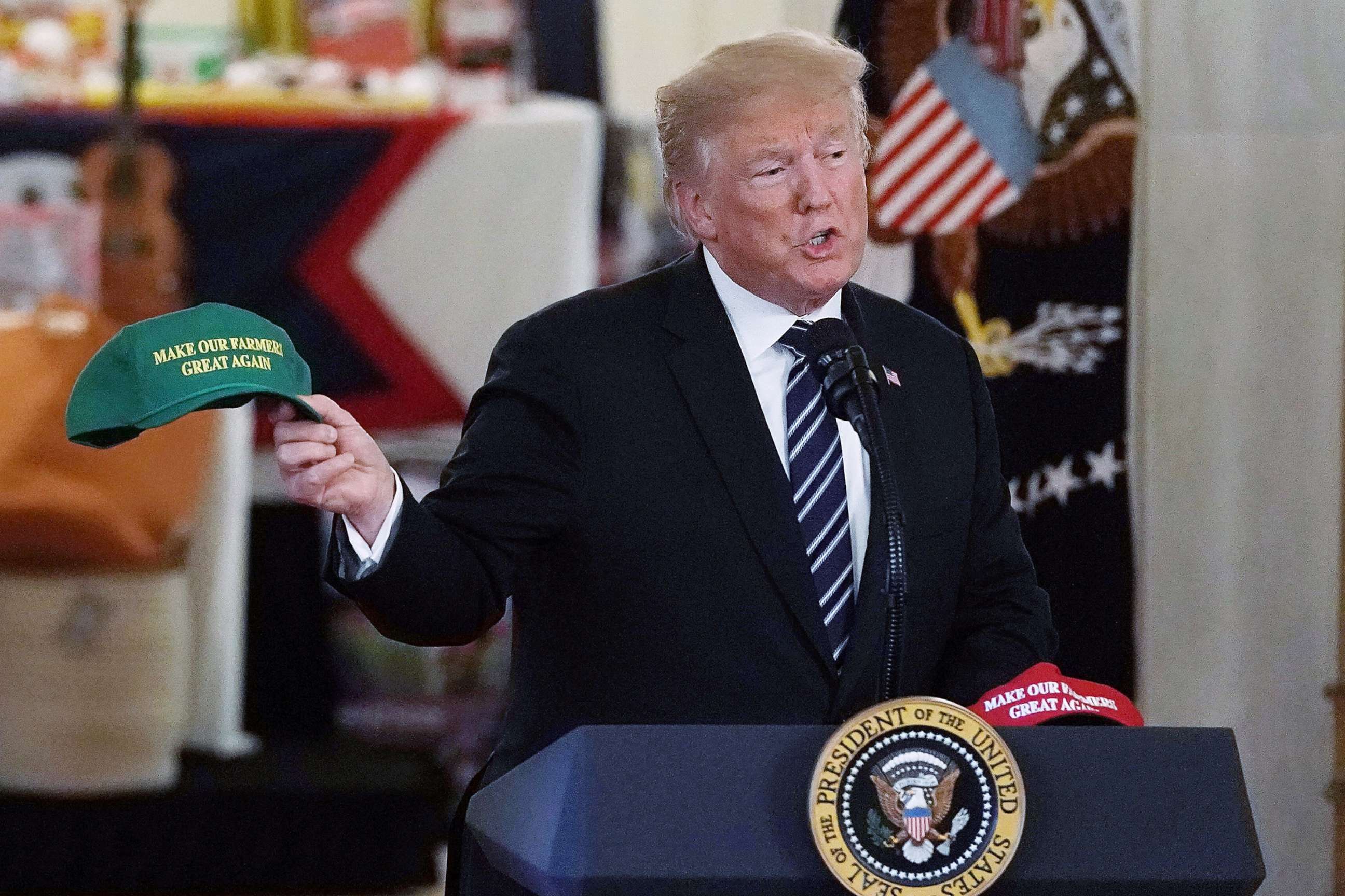 PHOTO: President Donald Trump holds up a "Make Our Farmers Great Again" hat as he speaks during the 2018 Made in America Product Showcase event, July 23, 2018, in the Cross Hall of the White House in Washington, D.C.