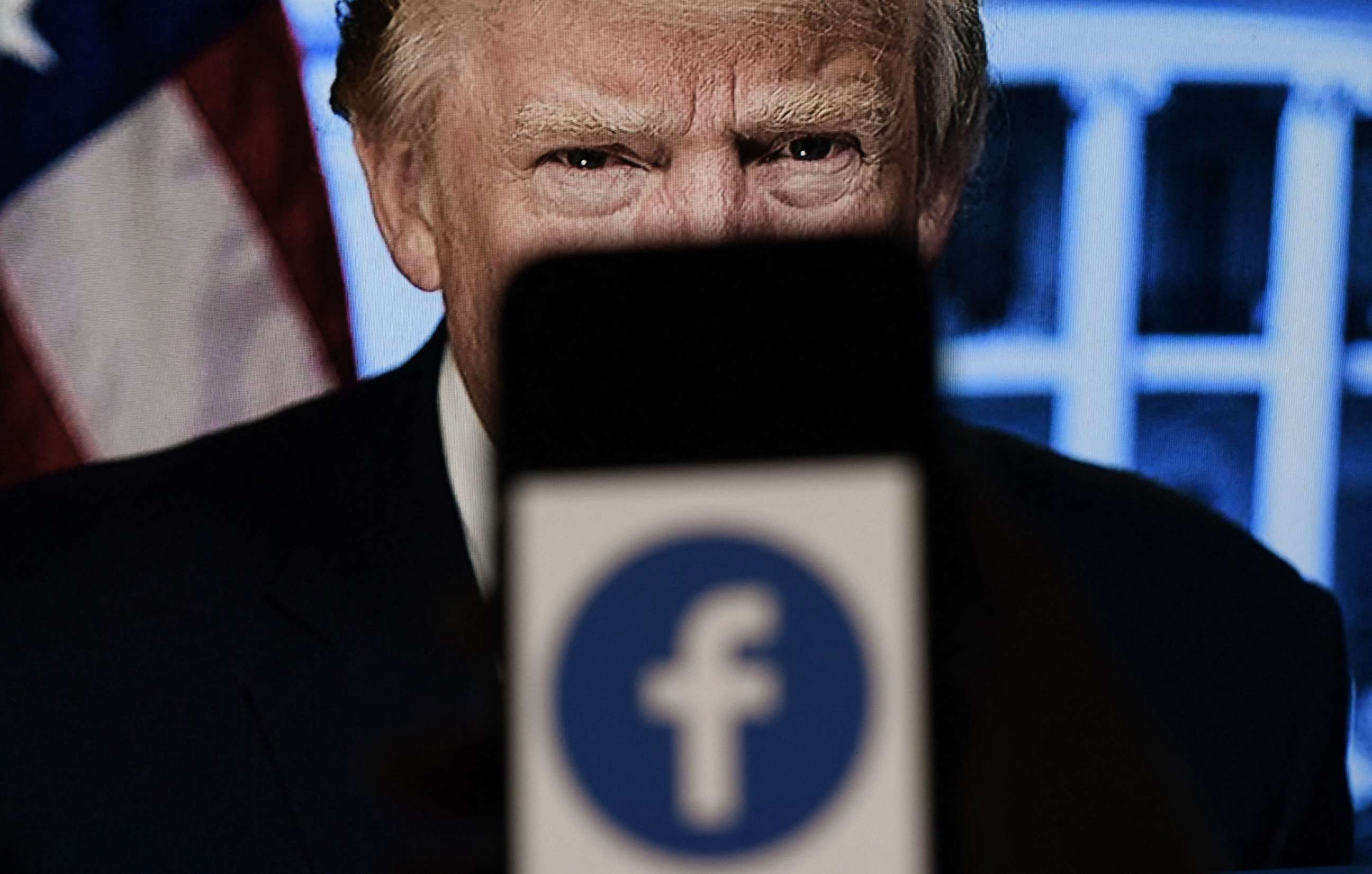 PHOTO: In this photo illustration, a phone screen displays a Facebook logo with the official portrait of former President Donald Trump on the background, on May 4, 2021, in Arlington, Va.