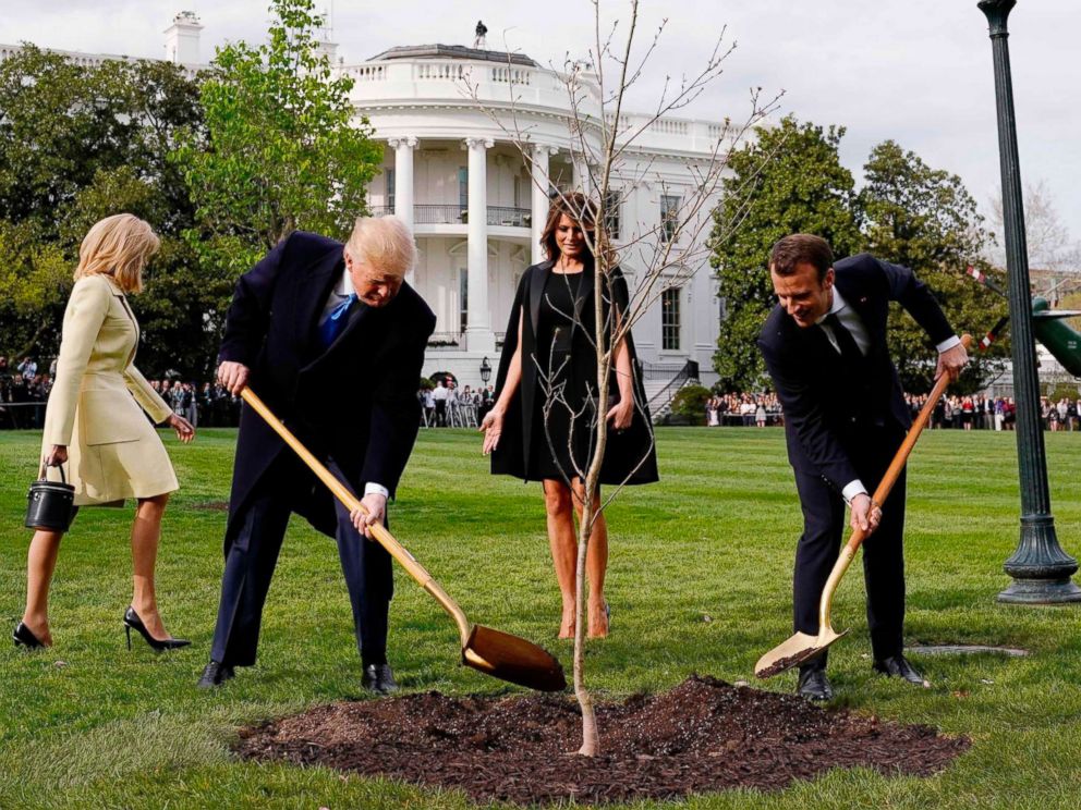 PHOTO: President Donald Trump and French President Emmanuel Macron shovel dirt onto a freshly planted oak tree as first lady Melania Trump and Brigitte Macron watch on the South Lawn of the White House in Washington, D.C., April 23, 2018.