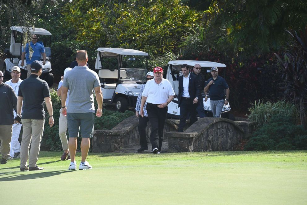 PHOTO: President Donald Trump walks onto the green at the Trump International Golf Course in Mar-a-Lago, Fla., during an invitation for U.S. Coast Guard service members to play golf, Dec. 29, 2017.