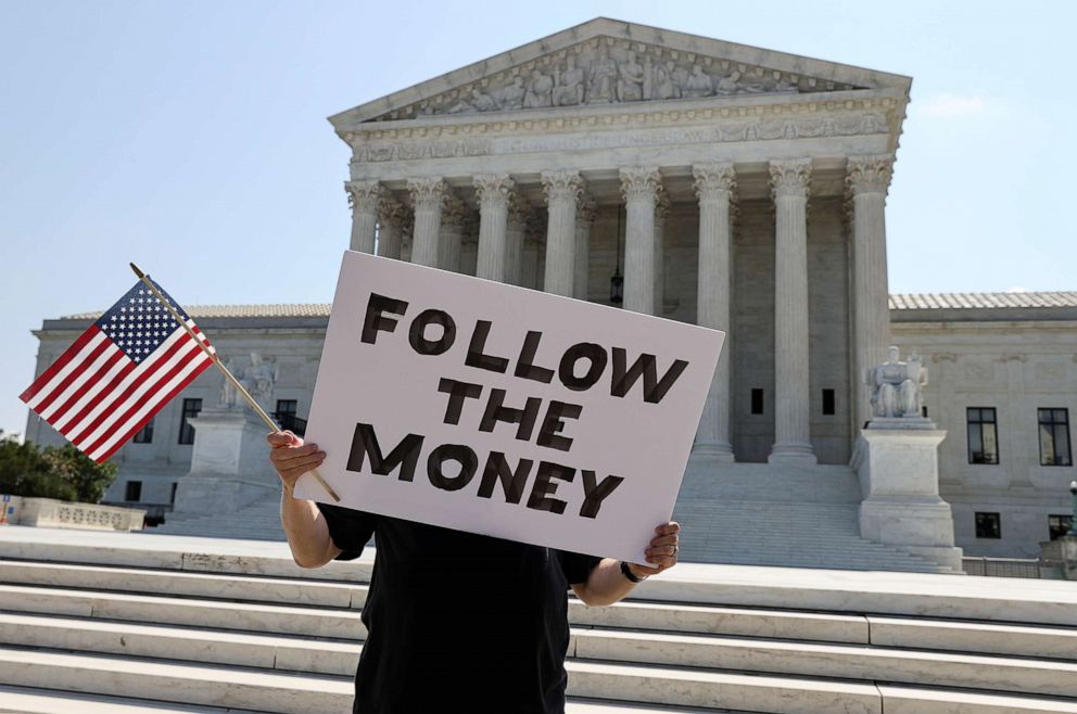 PHOTO: Bill Christeson holds a sign reading "follow the money" in anticipation of justices ruling on President Donald Trump's bid to block his financial records from being obtained by third parties, outside the Supreme Court in Washington, July 8, 2020. 
