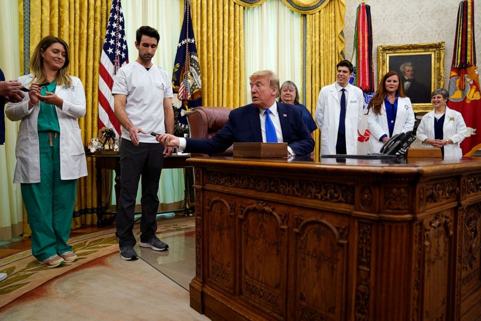 PHOTO: President Donald Trump hands a pen off after signing a proclamation in honor of World Nurses Day, in the Oval Office of the White House, May 6, 2020, in Washington.