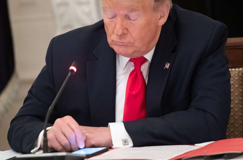 PHOTO: President Donald Trump uses his cellphone during a roundtable discussion with governors about the economic reopening of closures due to COVID-19, in the State Dining Room of the White House, June 18, 2020.