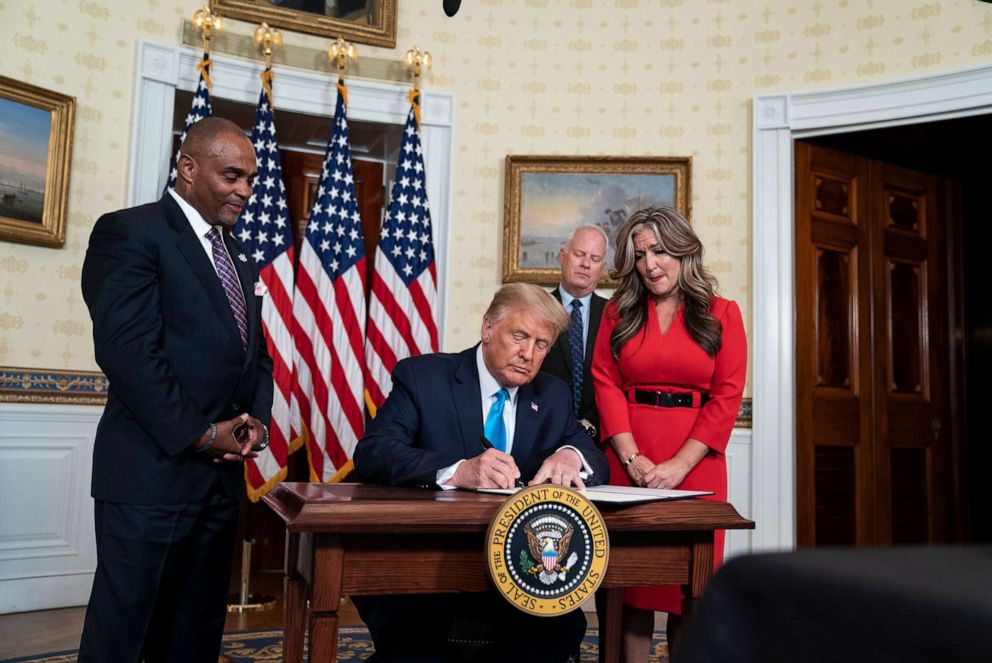PHOTO: President Donald Trump, joined by ex-convict and Hope for Prisoners CEO Jon Ponder, left, his wife Jamie, and FBI agent Richard Beasley, signs a pardon for Ponder in the Blue Room of the White House Aug. 25, 2020, in Washington, DC.