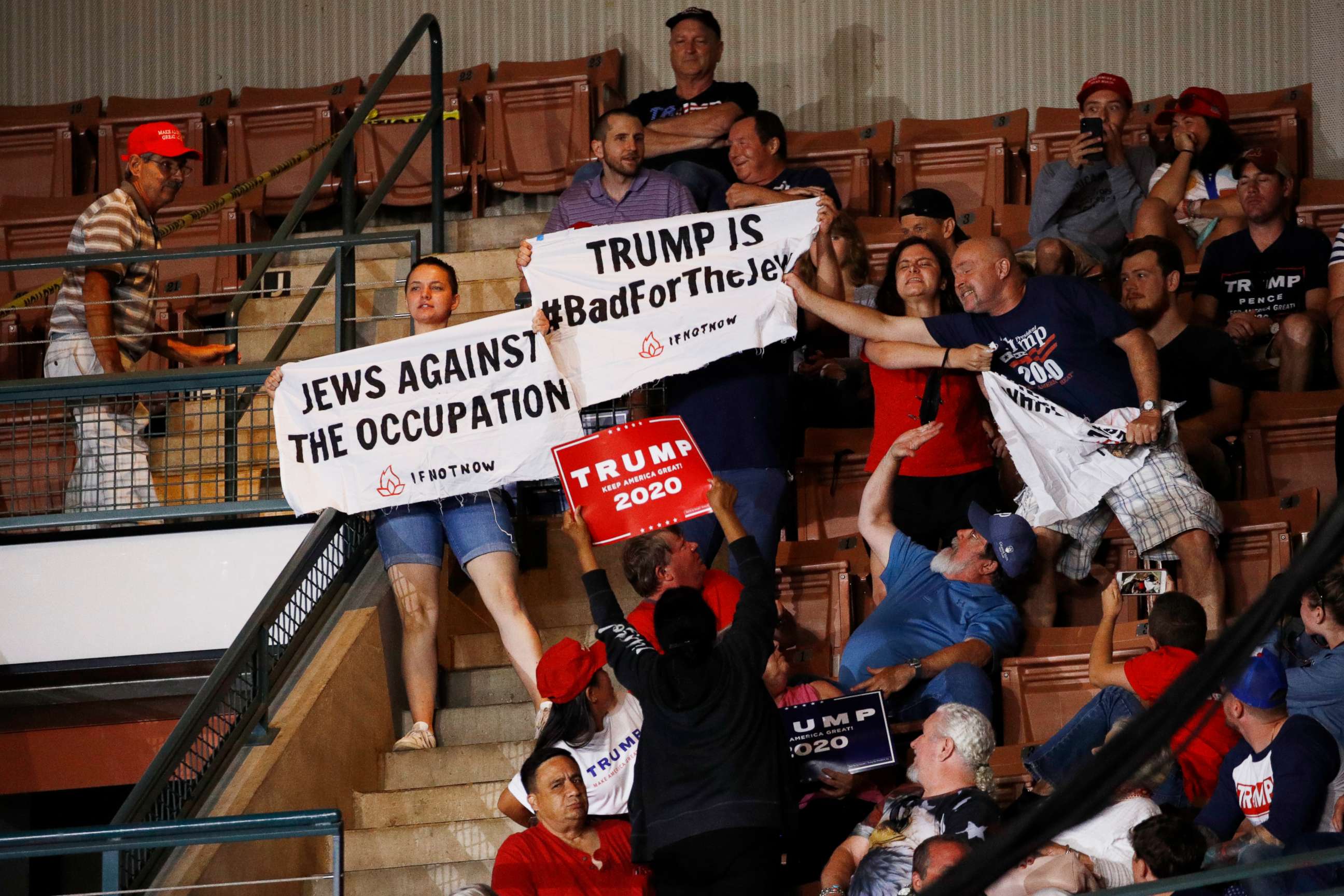 PHOTO: A Trump supporter, right, tries to grab a protesters' sign as President Donald Trump speaks at a campaign rally, Thursday, Aug. 15, 2019, in Manchester, N.H.