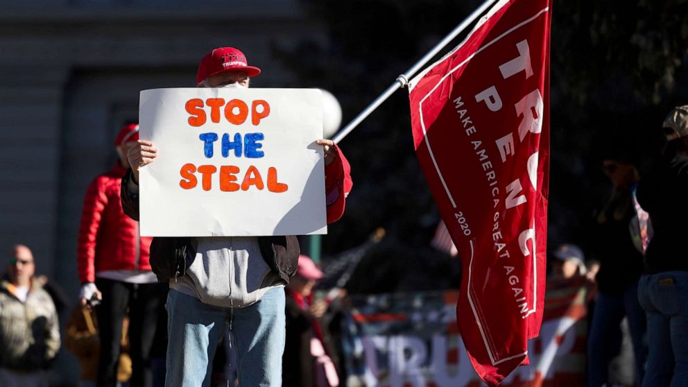 PHOTO: A Donald Trump supporter holds a Stop the Steal sign while gathering on the steps of the Colorado State Capitol to protest the election on January 6, 2021 in Denver, Colorado.