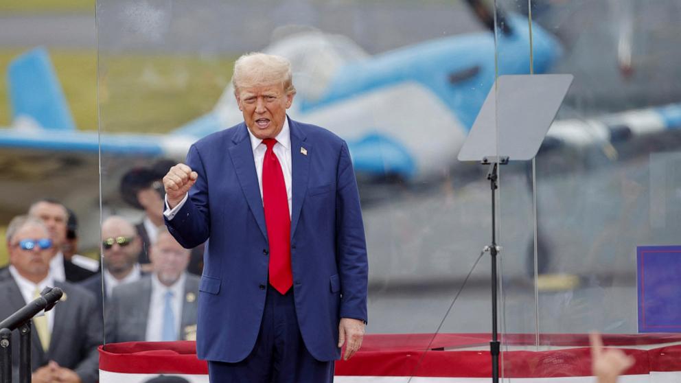 PHOTO: Republican presidential nominee and former President Donald Trump gestures from a bulletproof glass housing during a campaign rally, at the North Carolina Aviation Museum & Hall of Fame in Asheboro, North Carolina, Aug. 21, 2024. 